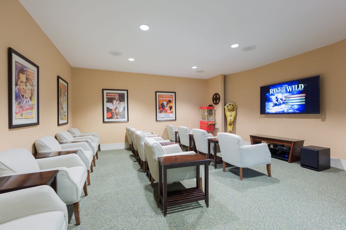 A cozy home theater room with comfortable seating, wall-mounted TV, and decorative posters.
