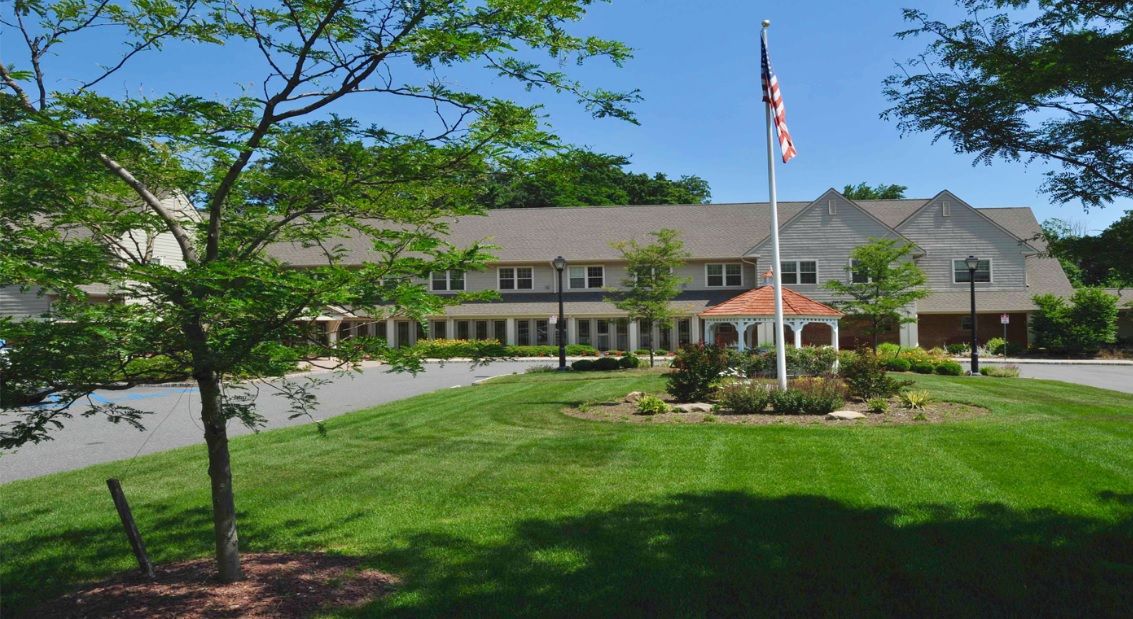 A large building with a neatly maintained lawn and an American flag flying on a flagpole.