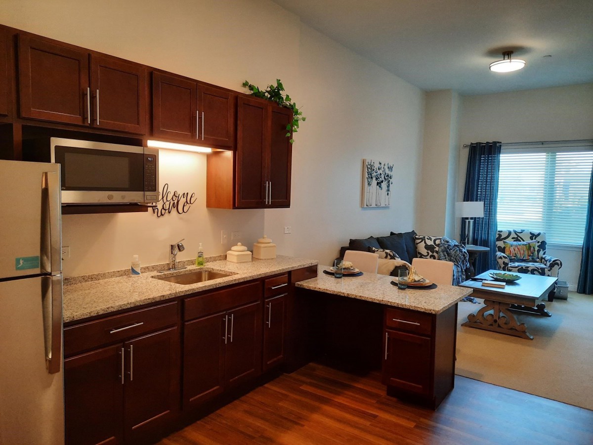 Modern apartment kitchen with dining area and view into the living room.