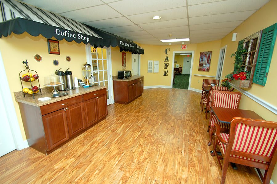 A cozy coffee shop interior featuring a seating area with wooden floors and yellow walls.