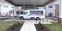 A small bus parked in front of a building entrance.