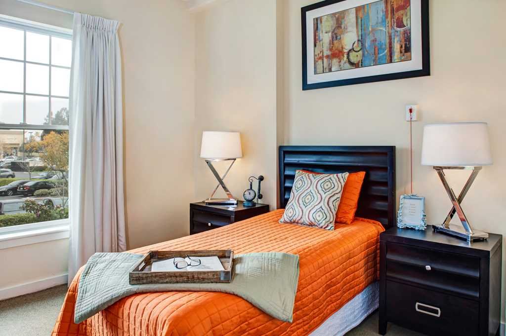 Cozy bedroom with a modern design featuring an orange bedspread and decorative accents.