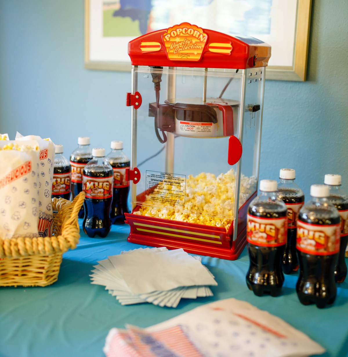 A party setup featuring a popcorn machine and an assortment of drinks on a table.
