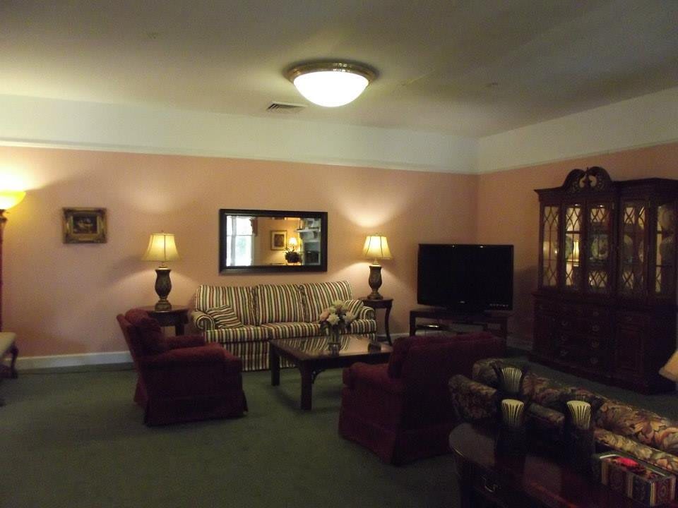 A cozy living room with a sofa, armchairs, and a television.