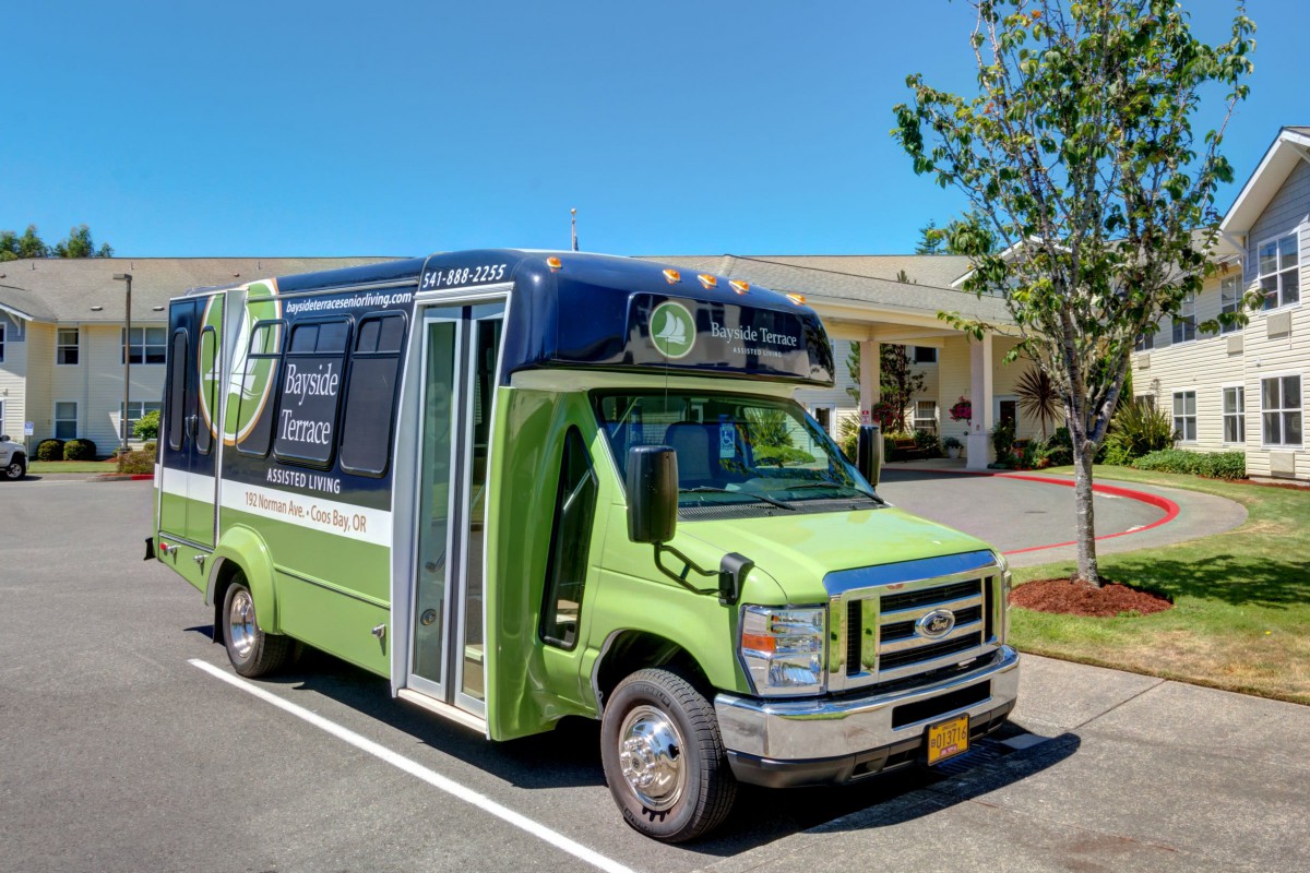 A green shuttle bus parked in a sunny parking lot.