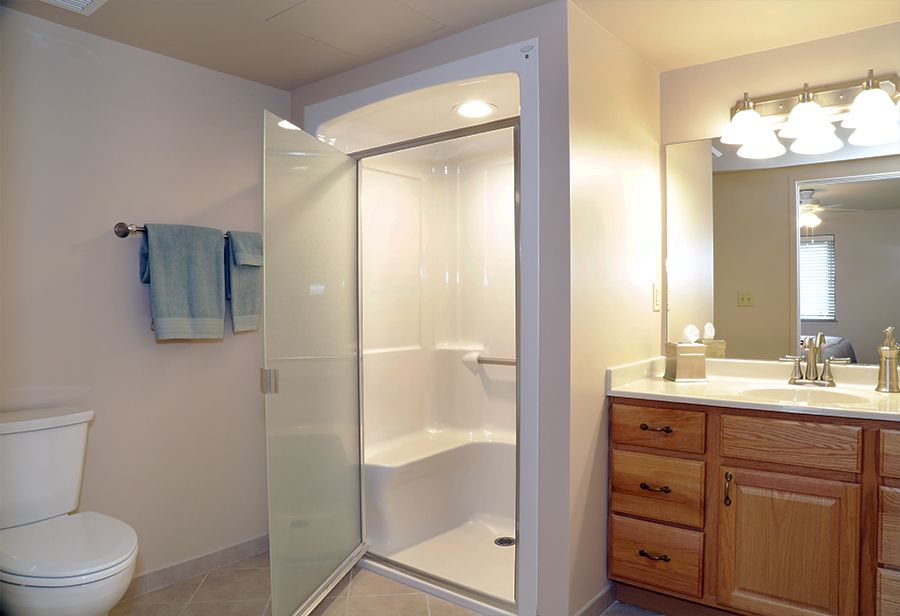 A modern bathroom featuring a walk-in shower with a glass door, wooden cabinets, and soft lighting.