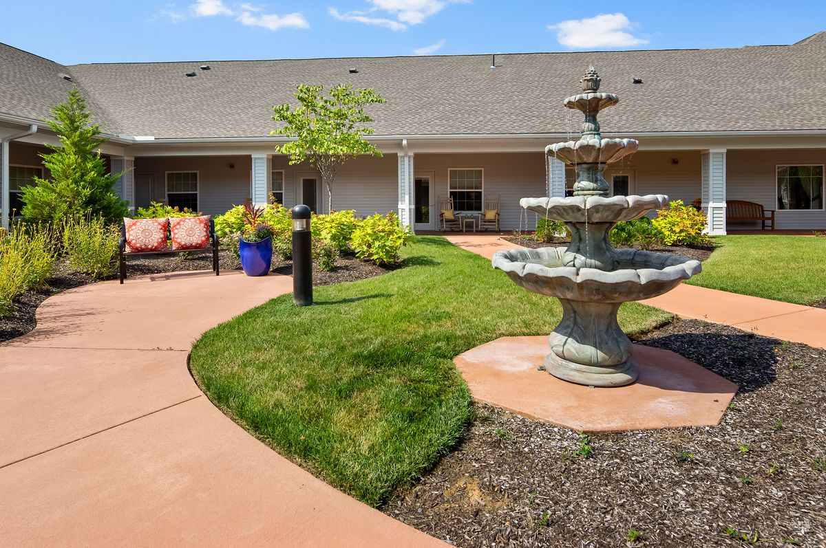 A serene courtyard with a central fountain, surrounded by manicured gardens and outdoor seating.