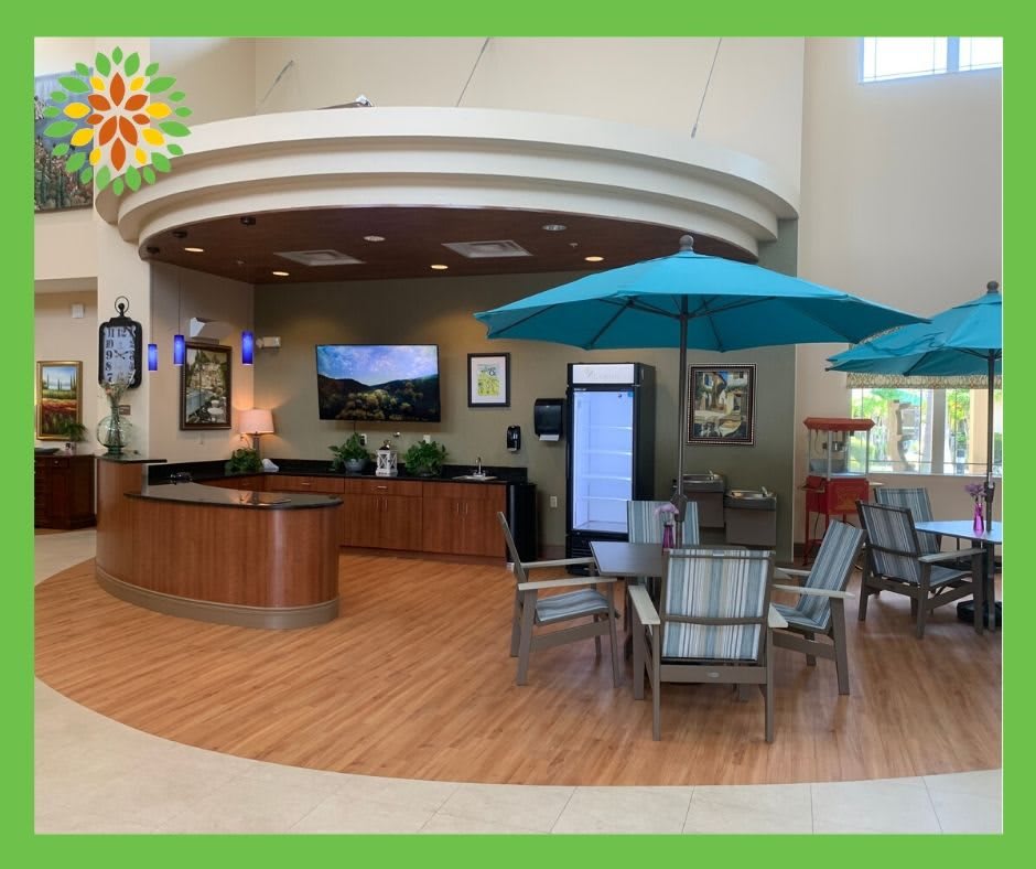 A spacious lobby with a reception desk, seating area, and large umbrellas indoors.