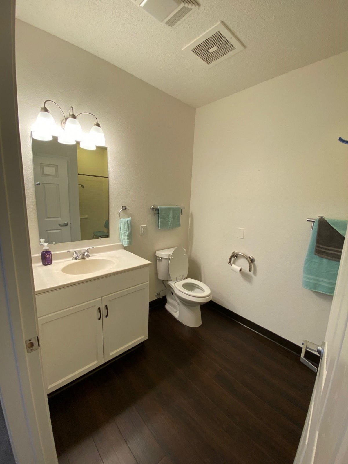 A clean and well-lit bathroom with a vanity, mirror, and toilet.