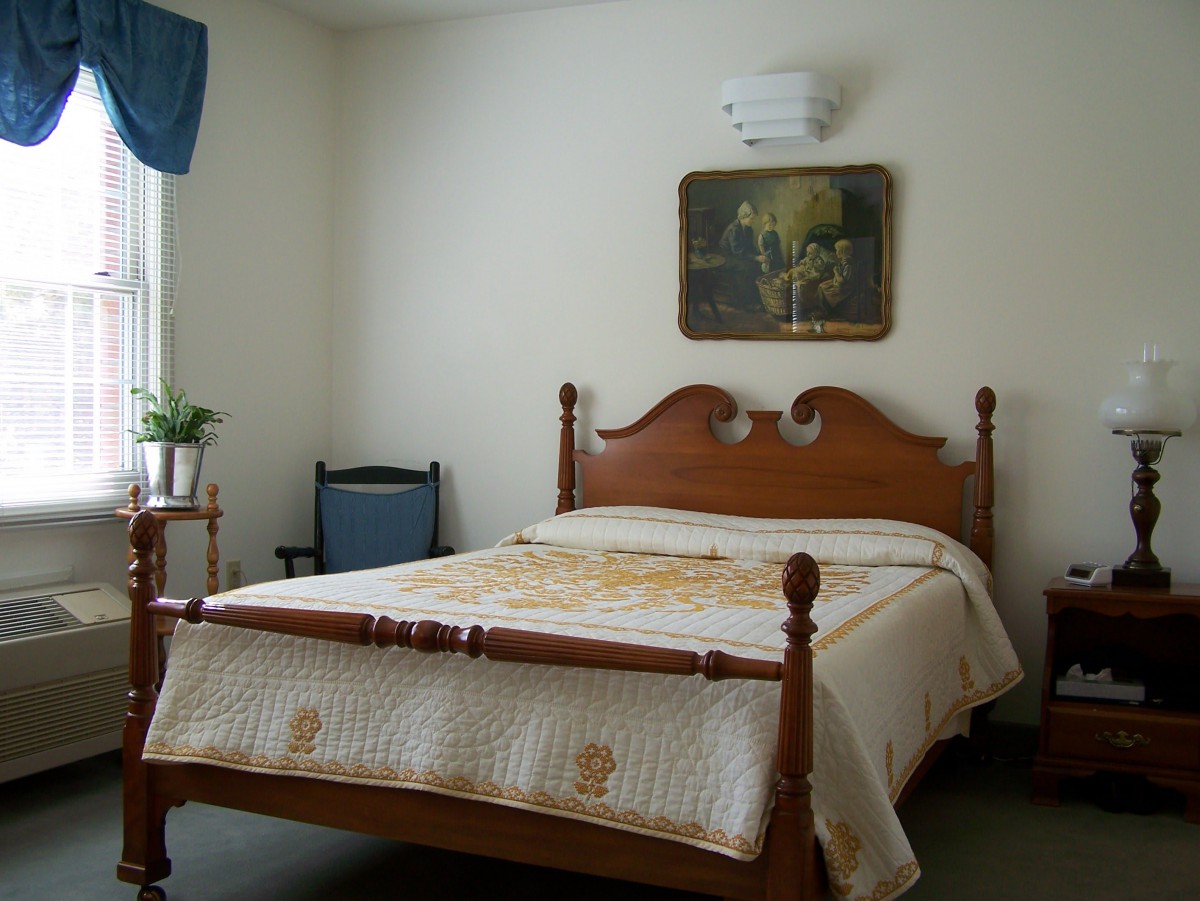 A cozy bedroom with a wooden bed, decorative quilt, and wall art.