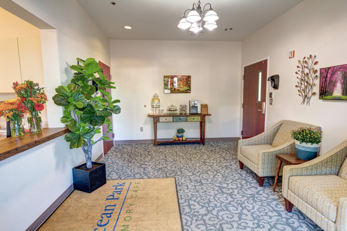 A welcoming lobby area with a comfortable armchair, potted plant, and a console table under a mirror.