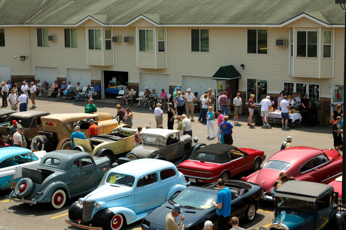 A lively car show featuring a collection of vintage and classic cars with attendees enjoying the event.