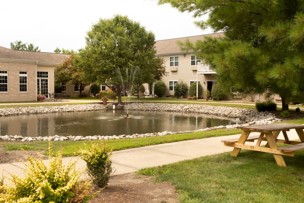 A serene courtyard with a pond surrounded by greenery and buildings.