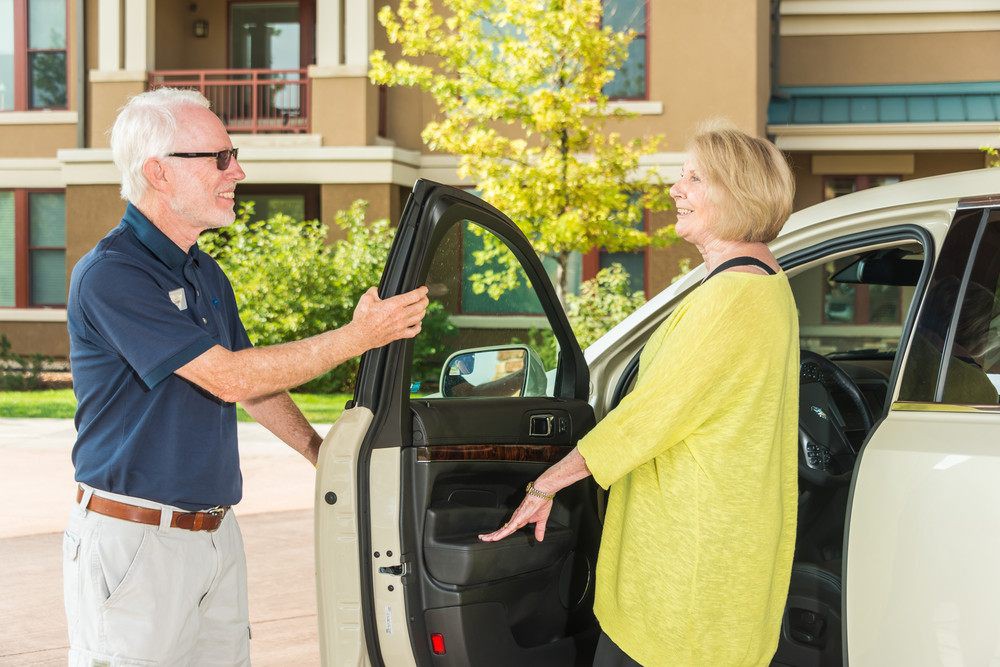 A man is opening a car door for a woman outside.