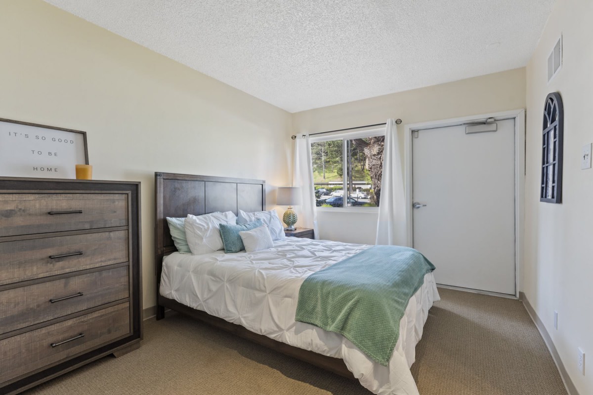 A cozy bedroom with a neatly made bed and a large window.