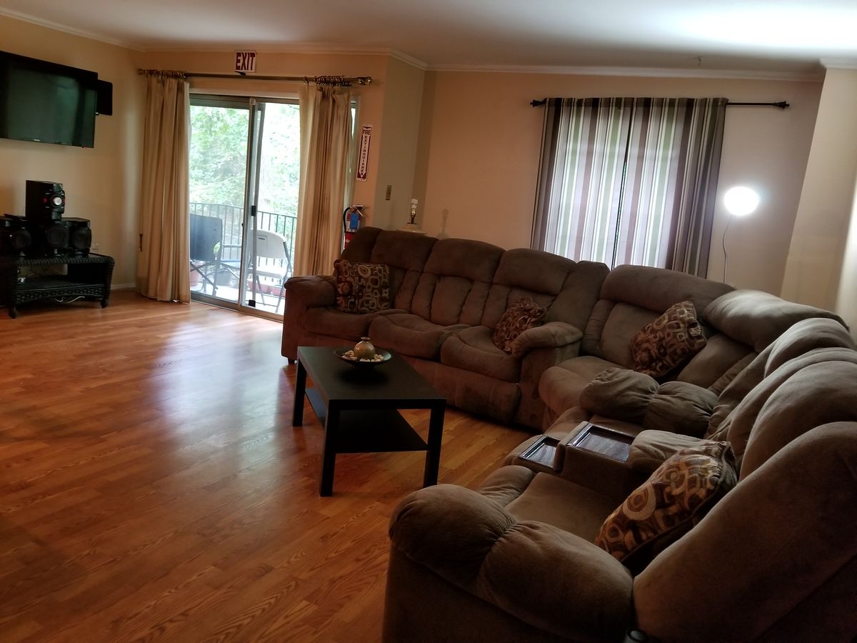 A cozy living room with a sectional sofa, hardwood floors, and a sliding glass door leading to an outdoor area.