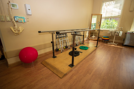 A well-equipped rehabilitation space featuring a balance bar and various exercise tools.