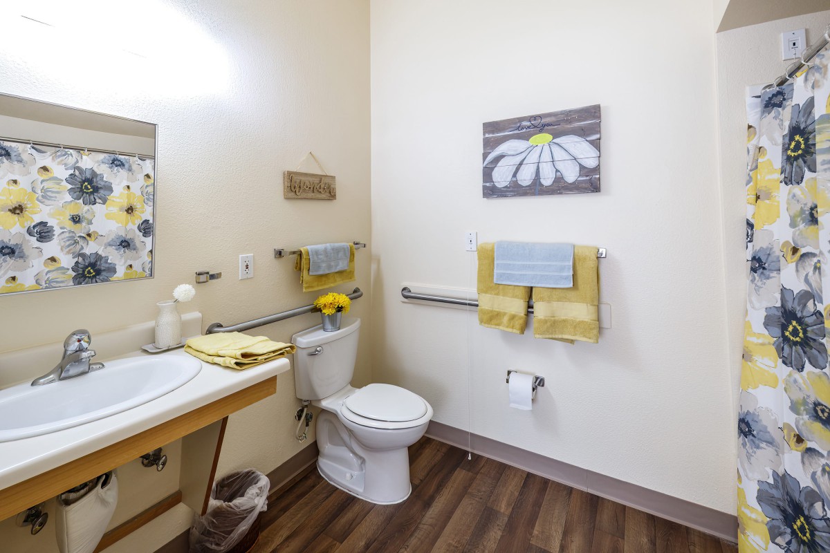 A well-organized bathroom featuring a toilet, sink, and decorative elements such as wall art and coordinated towels.