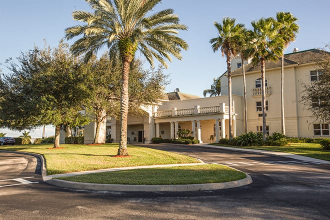 A hotel entrance surrounded by palm trees and well-maintained landscaping.