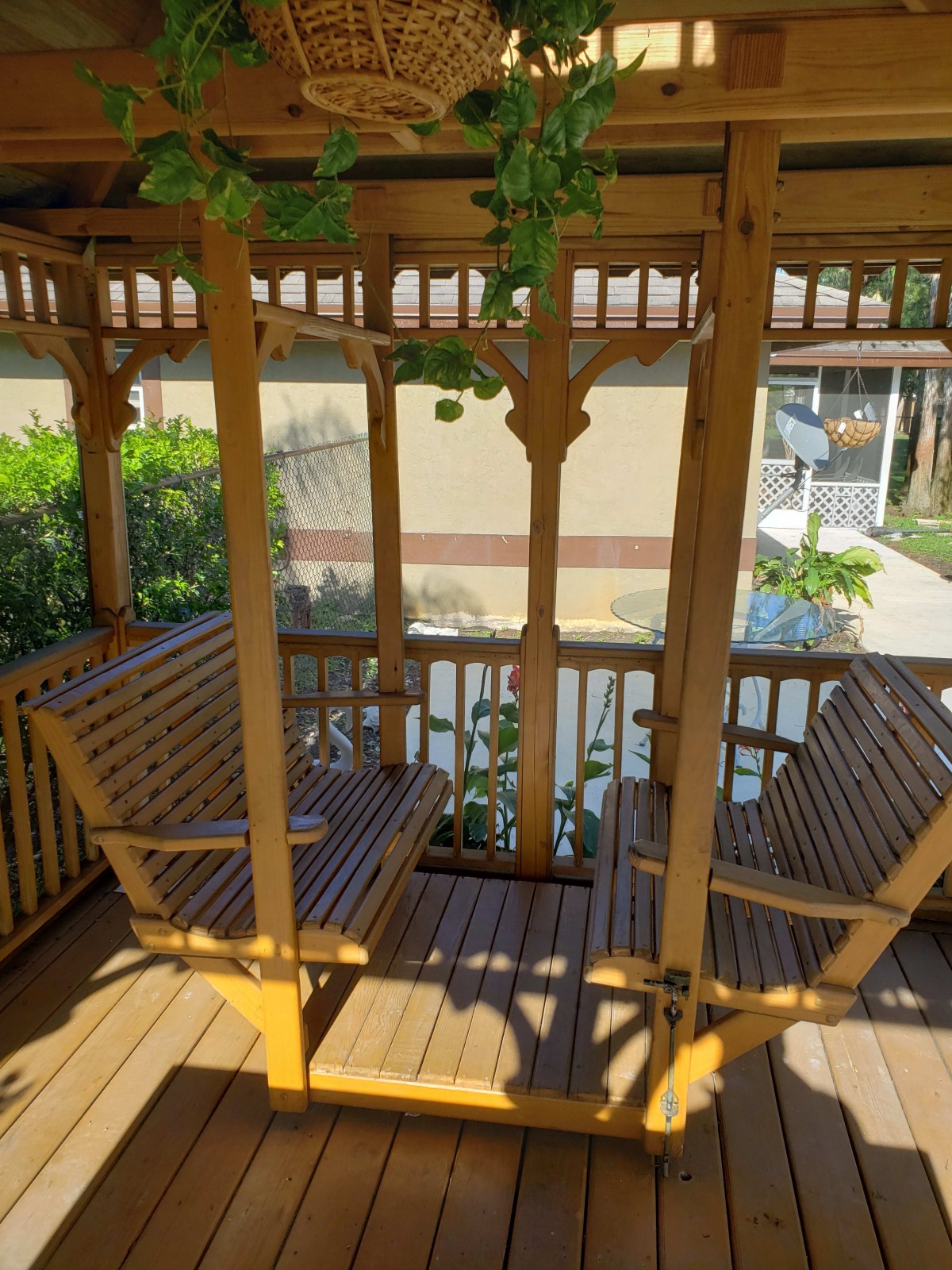A cozy wooden gazebo with seating, nestled in a garden setting.