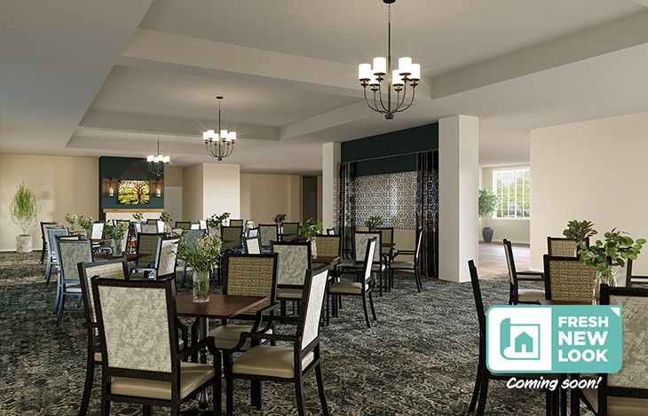 Elegant dining area with neatly arranged tables and chairs, illuminated by stylish chandeliers.