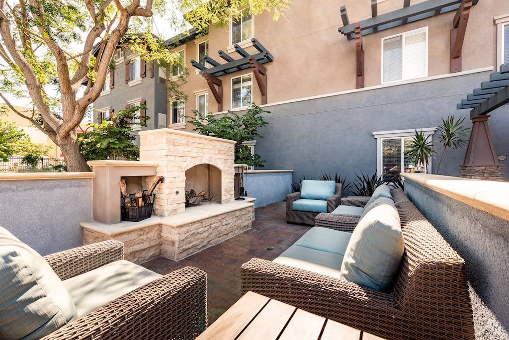 A cozy outdoor patio with comfortable wicker furniture and a built-in brick fireplace.