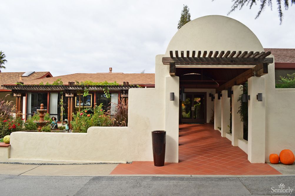 A view of an entrance with a covered walkway and garden.