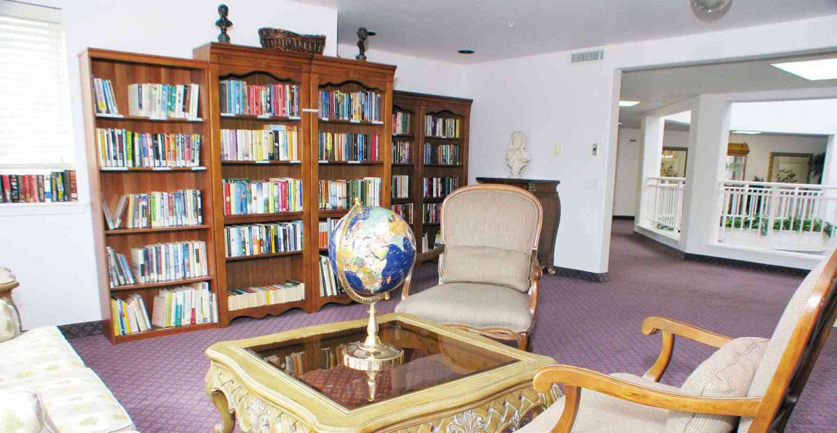A cozy library corner with bookshelves, a globe on a coffee table, and an armchair.