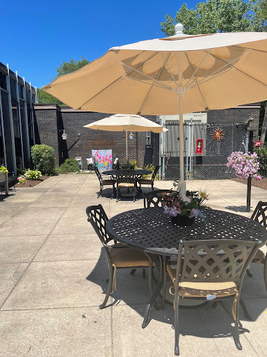 A sunny outdoor patio area featuring tables with umbrellas and blooming flowers.