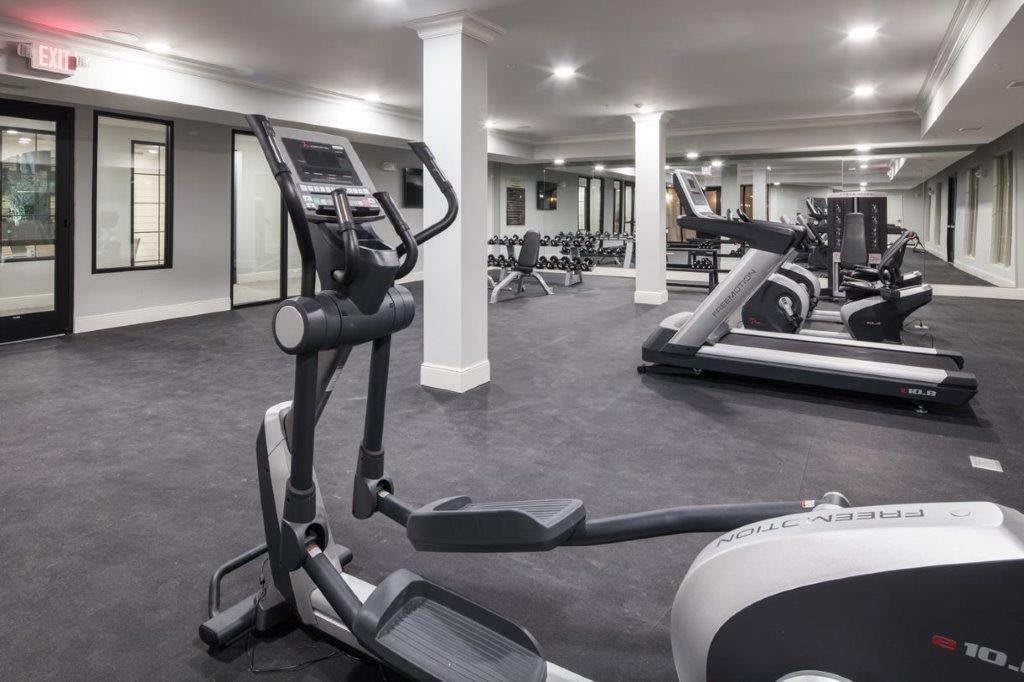 A modern gym with various exercise equipment including treadmills and an elliptical machine.