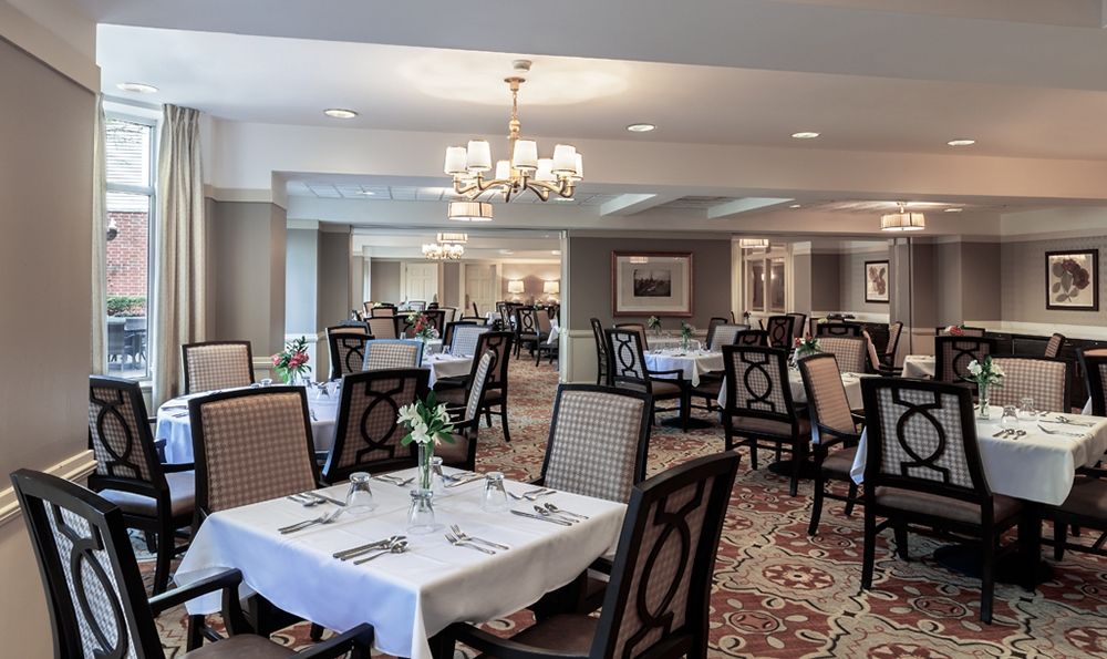 A elegantly designed restaurant dining area with neatly arranged tables and chairs, illuminated by a chandelier.
