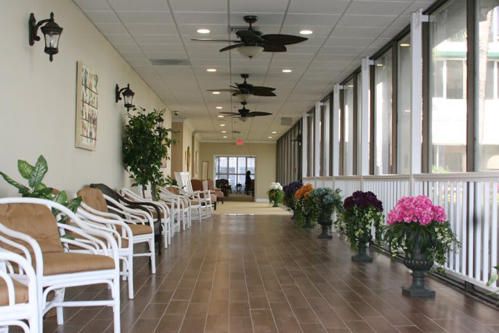 A well-lit hallway with chairs, plants, and ceiling fans.