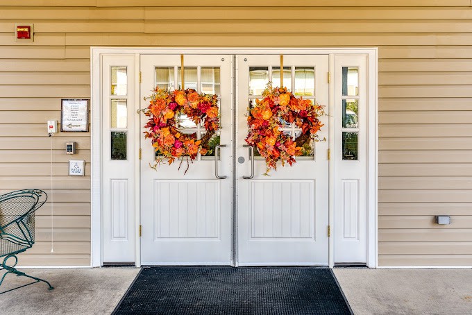 A pair of white double doors decorated with vibrant autumn wreaths.