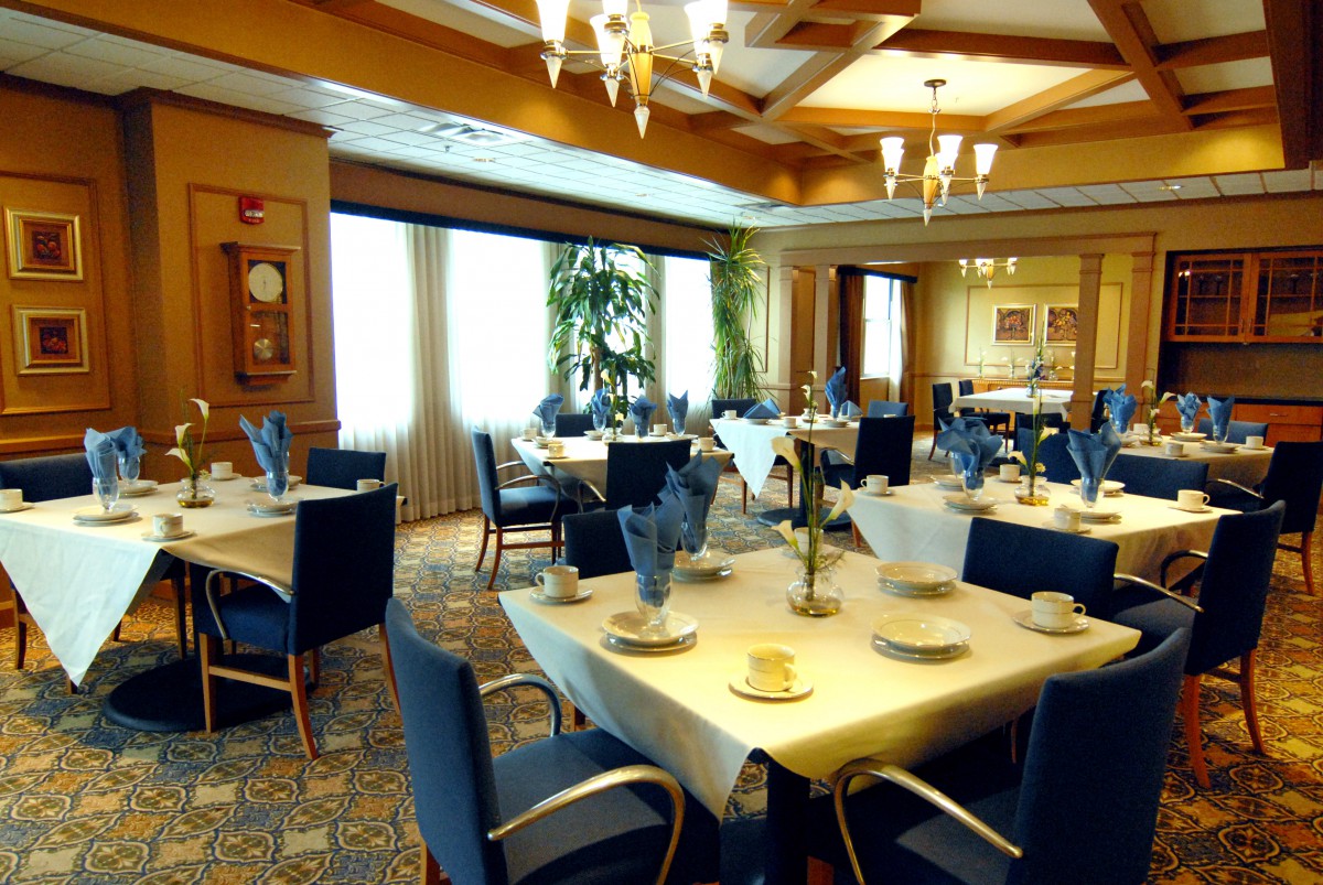 An elegant dining room with neatly arranged tables and chairs, set for a formal meal.