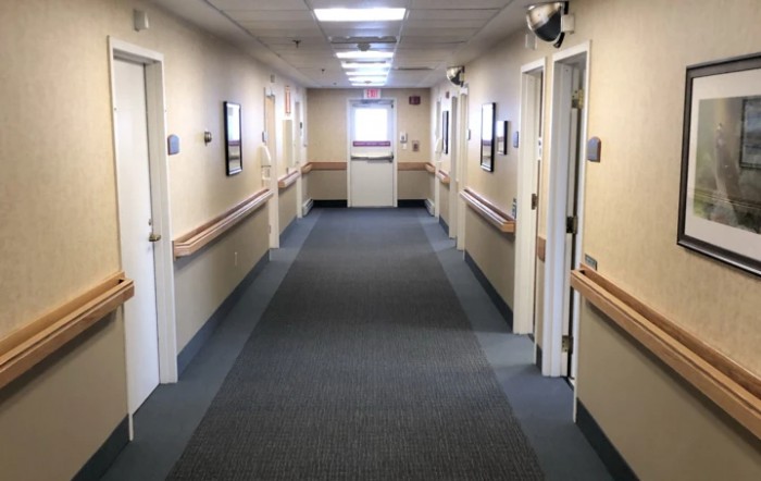 A well-lit hospital corridor with doors on either side.