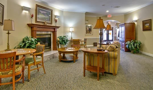 A cozy lobby interior with seating, tables, and a fireplace.