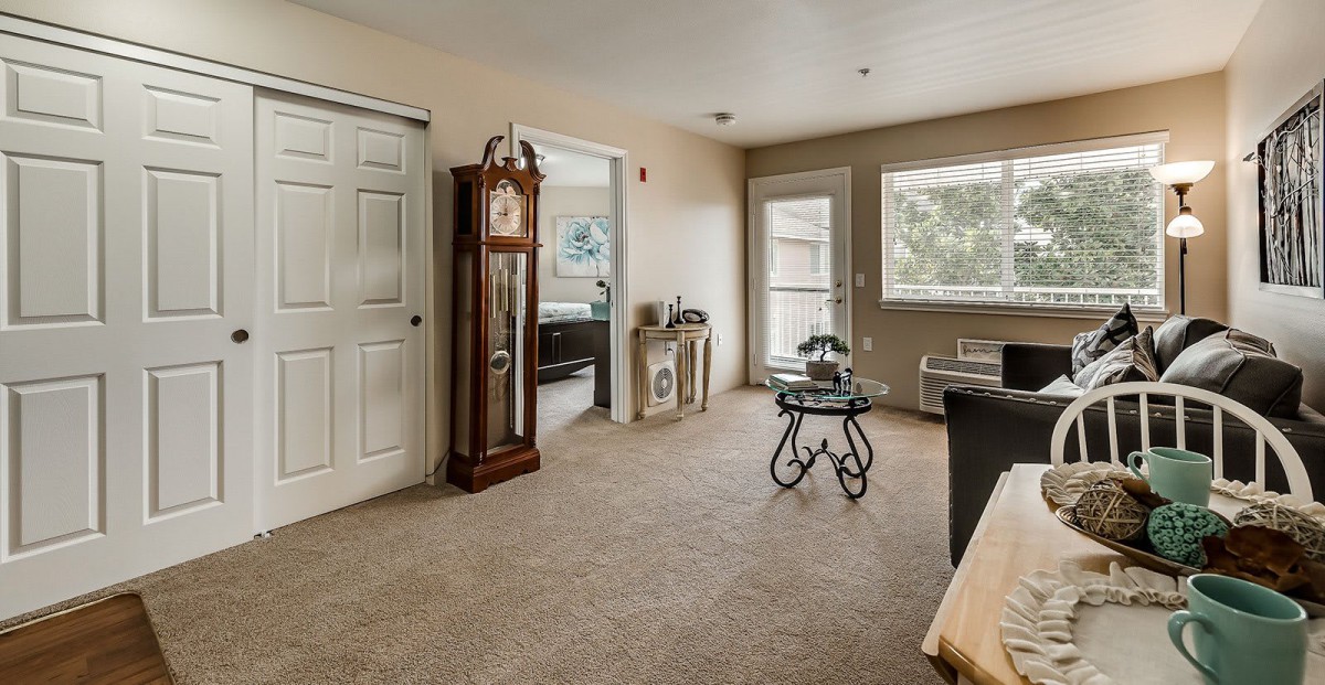 A cozy living room with a grandfather clock and large windows.