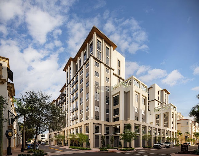 A modern urban building with a clear blue sky and surrounding trees.