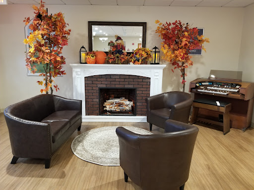 A cozy living room setup adorned with autumn decorations, featuring a warm fireplace and comfortable seating.