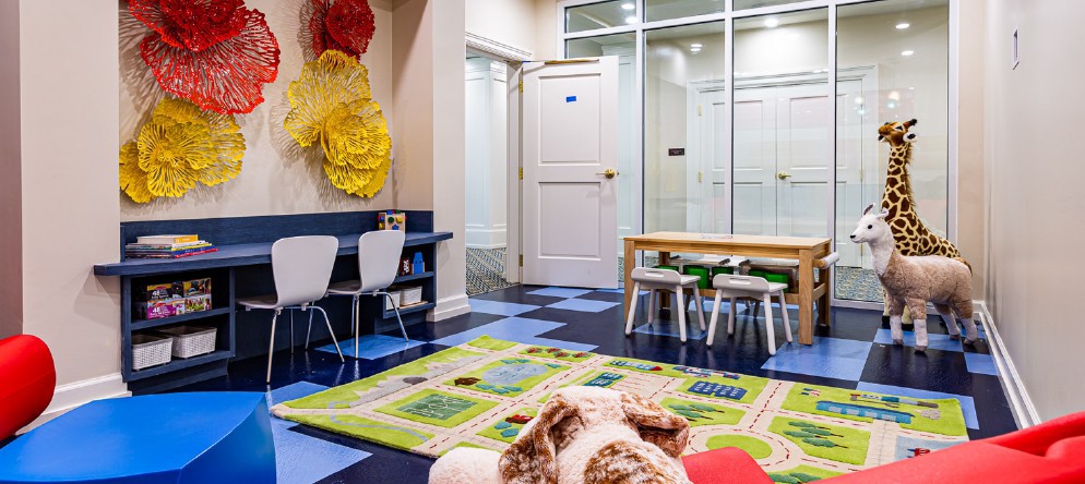 A colorful children's playroom with tables, chairs, and toys.