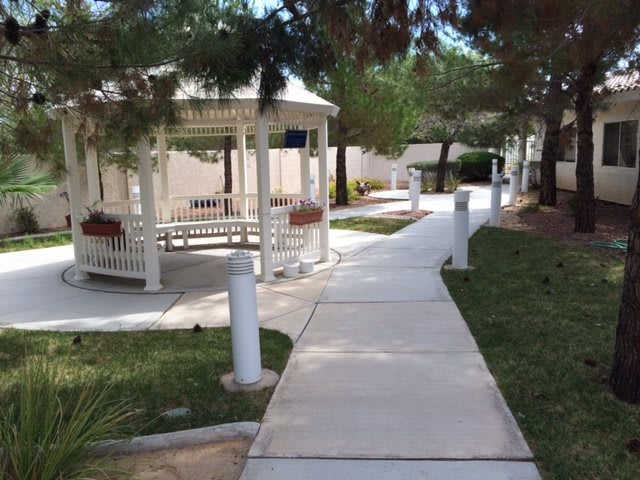 A peaceful outdoor pathway with a gazebo surrounded by greenery.