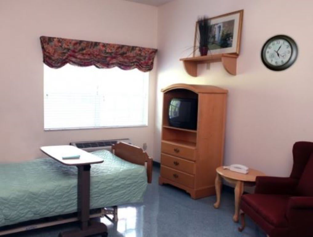 A hospital room with a single bed, television, and basic furniture.