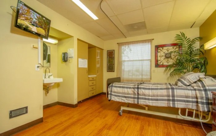 A hospital room with a single bed and medical amenities.