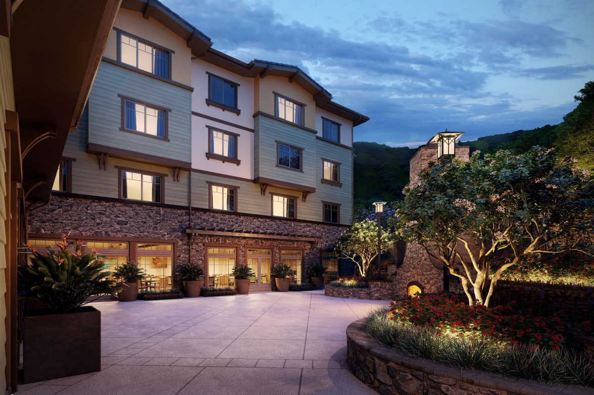 An elegant hotel building at dusk with illuminated windows and a landscaped courtyard.