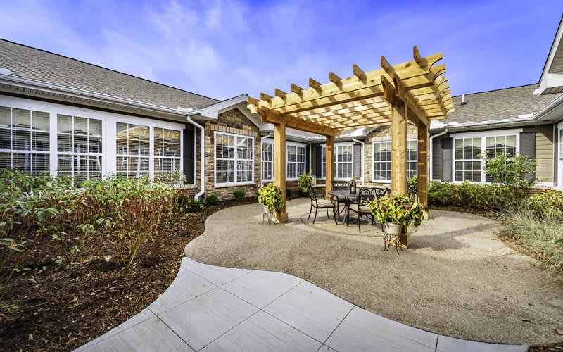 A beautifully landscaped patio featuring a wooden pergola and outdoor seating.