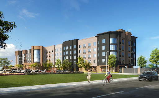 A modern residential building featuring sleek architecture and green landscaping, set in an urban environment.