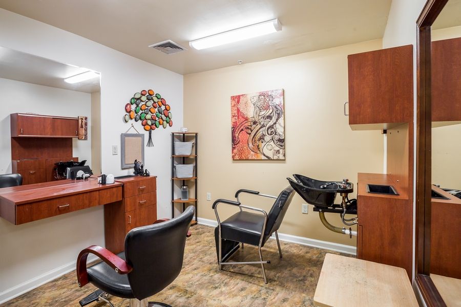 A cozy hair salon featuring chairs, mirrors, and colorful artwork on the walls.