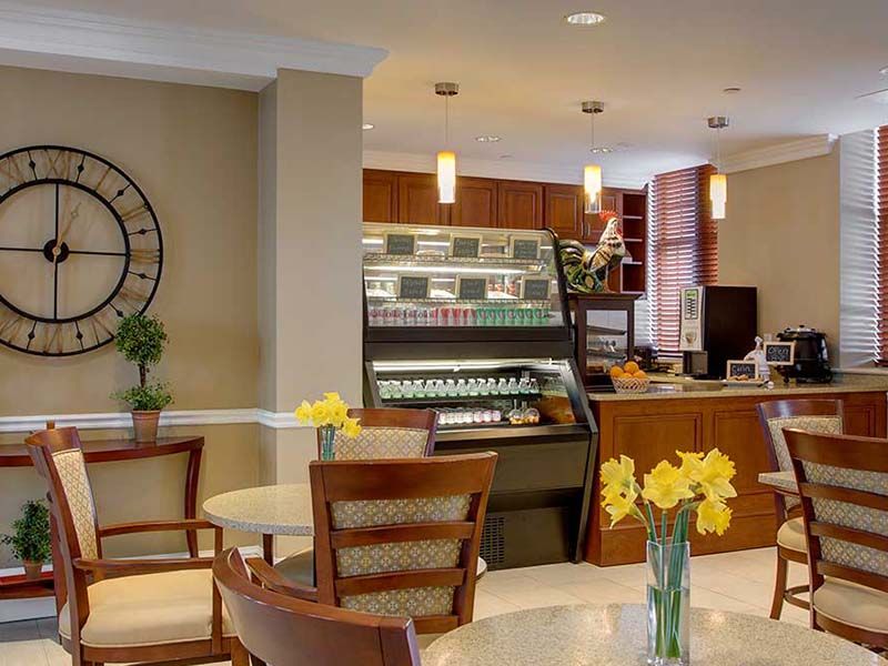 A modern cafe interior with seating and a display counter, featuring fresh flowers on the tables.