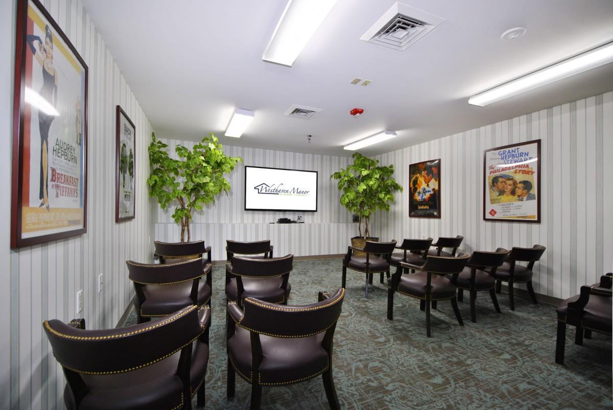 A small conference room with arranged seating and a projector screen.