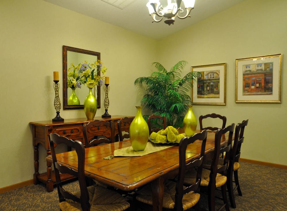 A well-decorated dining room featuring a wooden table and chairs, decorative vases, and wall art, with an indoor plant adding a touch of greenery.